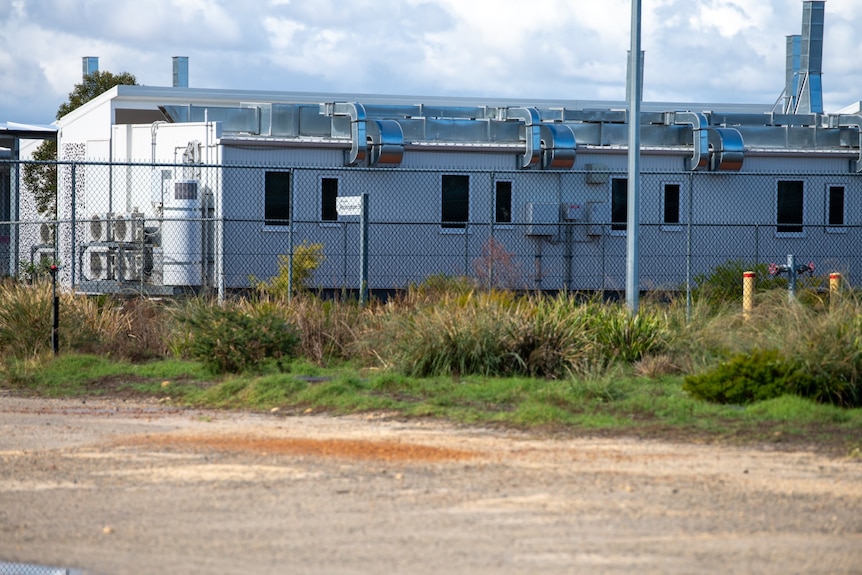 A building is seen behind a wire fence