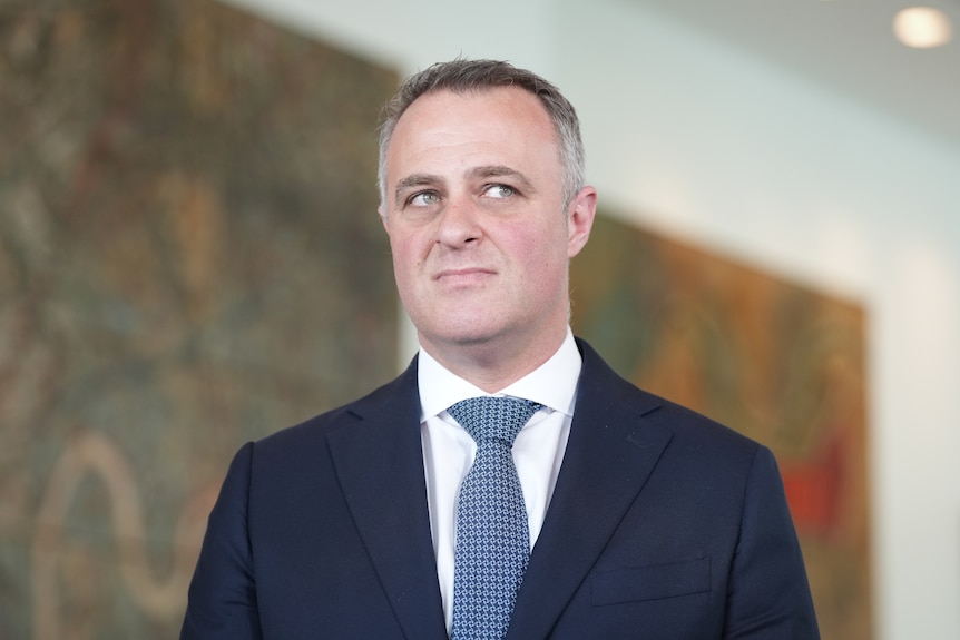 Shadow Treasurer Tim Wilson in suit and tie looks to the side.