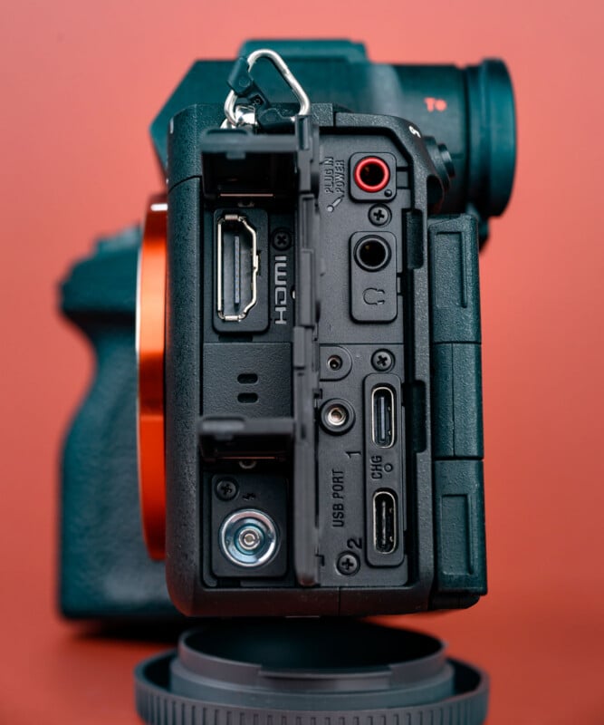 Close-up of a digital camera’s side panel showing various input and output ports, including HDMI, microphone, headphone, USB, and multi ports, with a red background.