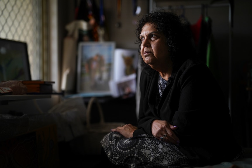A woman staring out a window with a solumn expression.