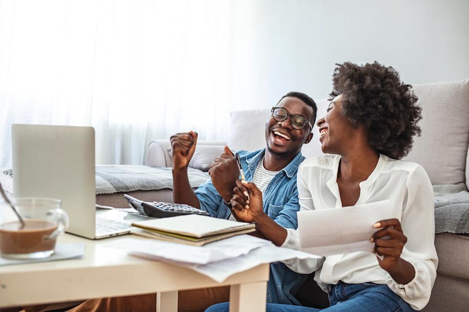 Two people celebrating while looking at a laptop.