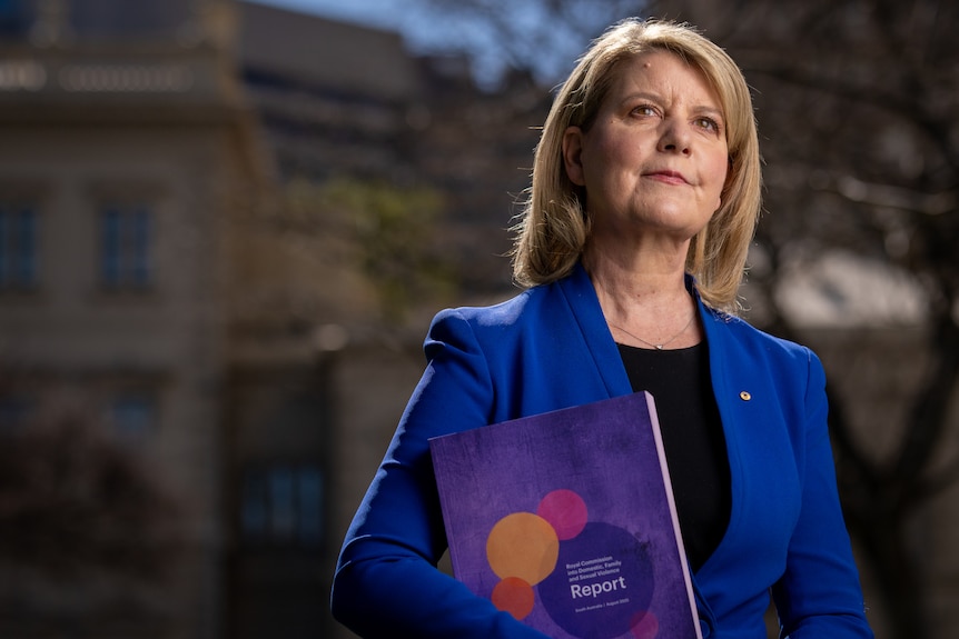A professonal holding a report and looking into the distance.