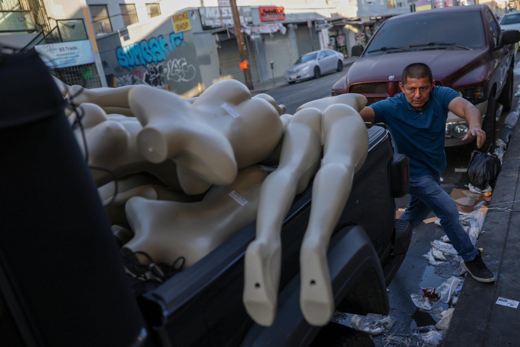 Joel Galvez scrambles to load a pile of mannequins into his truck