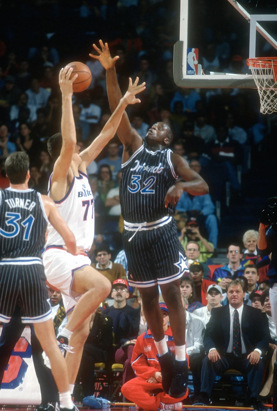 Basketball player in a pinstripe uniform attempts to block a shot during a game
