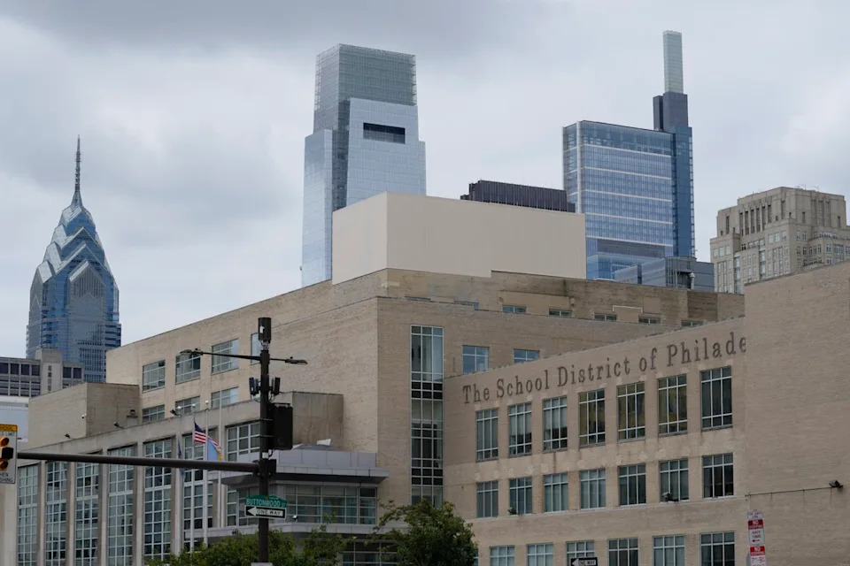 Shot of large beige building in foreground with glass skyscrapers in background