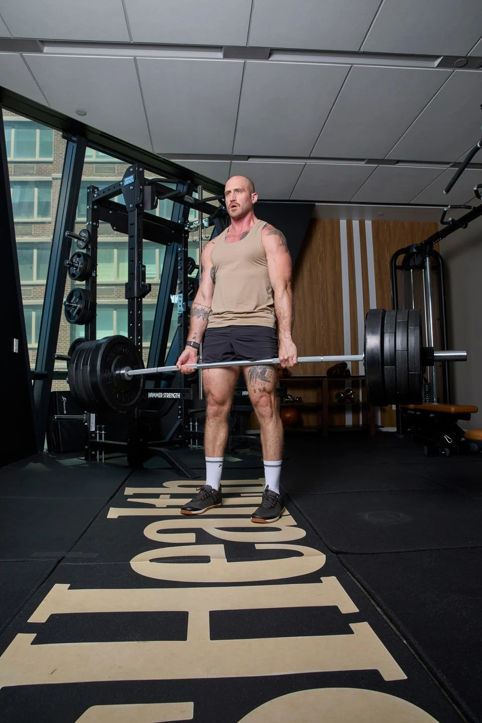 Man lifting heavy barbell in gym with weightlifting equipment.