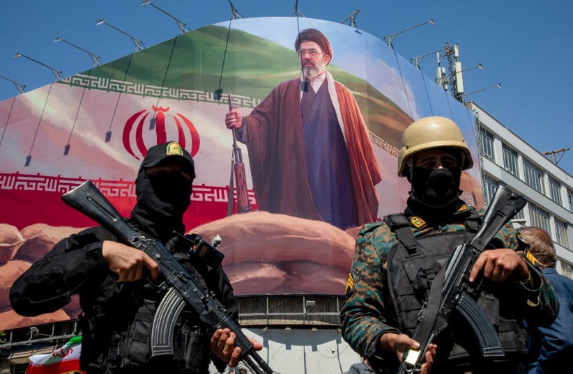 MEMBERS OF the Iranian security forces stand guard under a large portrait of Iran’s new Supreme Leader, Mojtaba Khamenei.