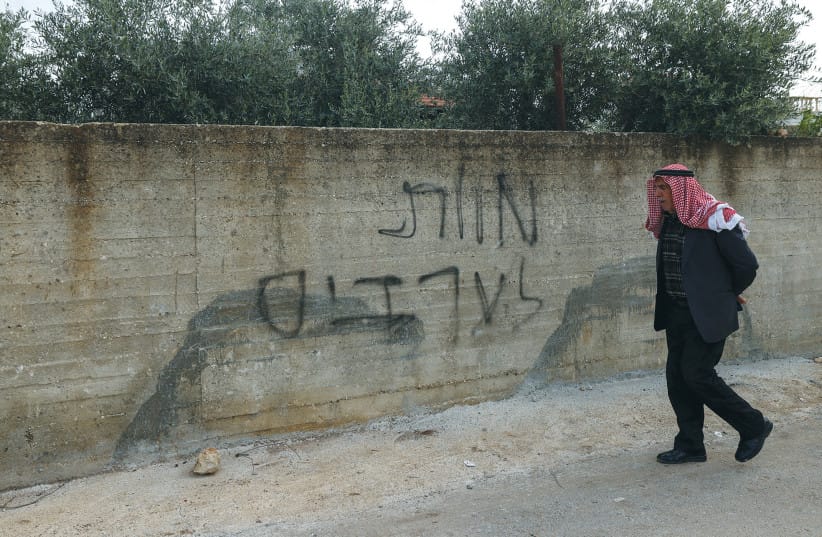 A PALESTINIAN man walks past Hebrew graffiti that reads, ‘Death to Arabs,’ on the wall of a home allegedly damaged house by Israeli settlers in the village of Deir al-Hatab in the West Bank, in March 2026.