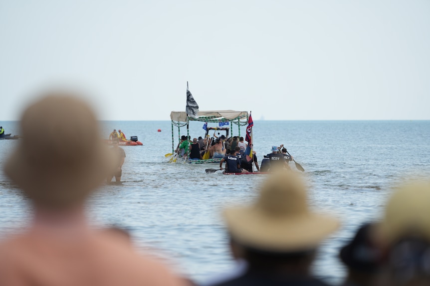 Group of people paddle with oars in boat made of beer cans