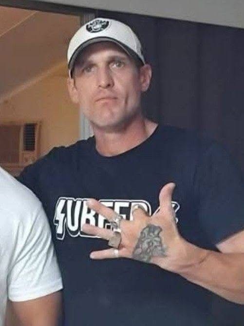 A man with tattoos on his hand wears a serious facial expression.
