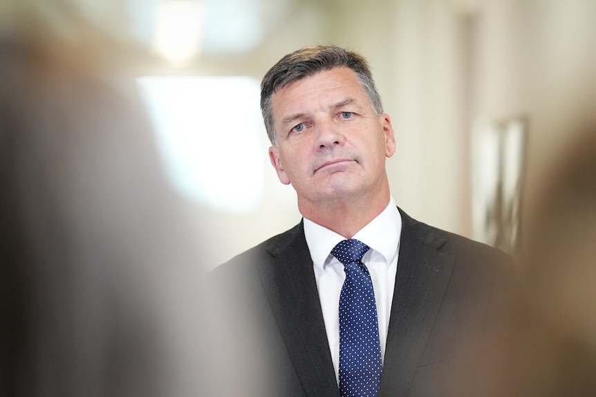 A headshot of Angus Taylor looking at the camera with a neutral expression.