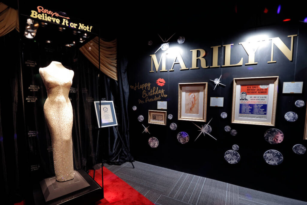 Image shows Marilyn Monroe's iconic 'Happy Birthday' dress on display surrounded by other items and artifacts at Ripley's Believe it or Not! Museum in Grand Prairie.