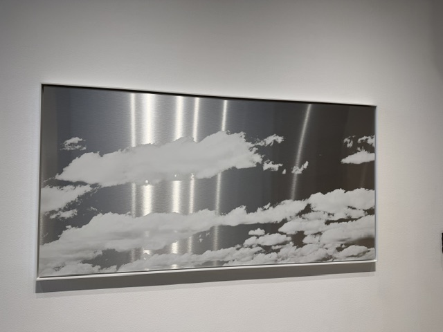 Brushed metal artwork depicting clouds displayed in the Heavy Metal exhibition at Los Angeles Municipal Art Gallery.