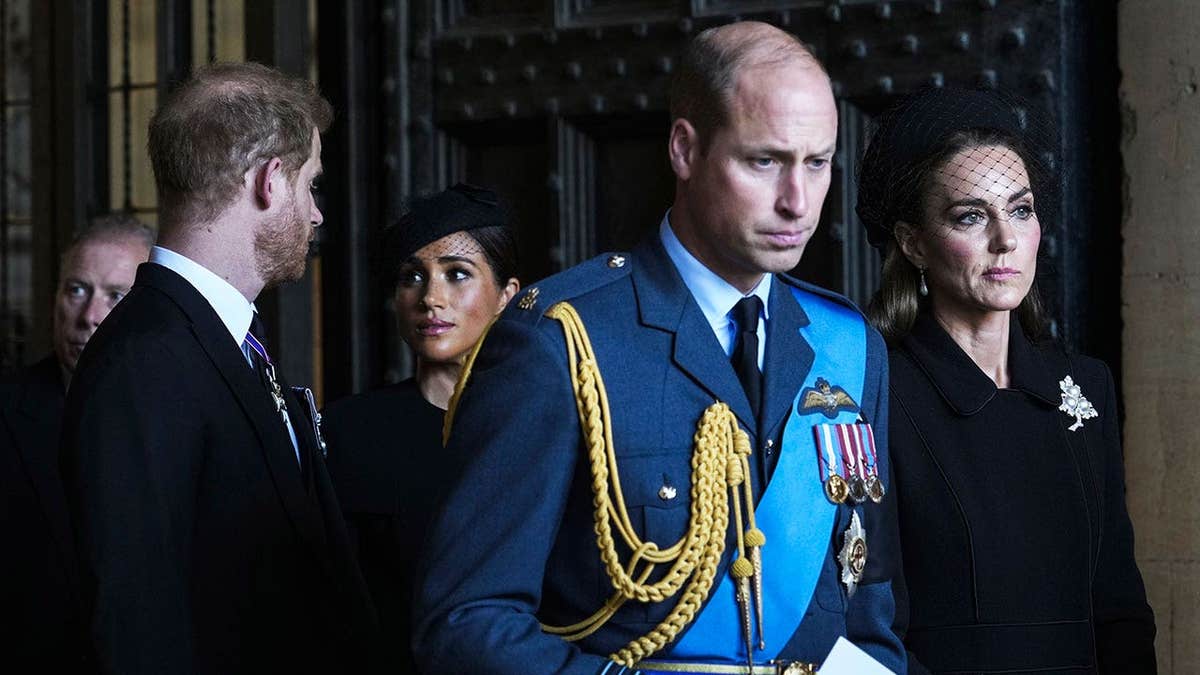 The Duke and Duchess of Sussex walking behind the Prince and Princess of Wales as they all look serious during Queen Elizabeth's funeral.