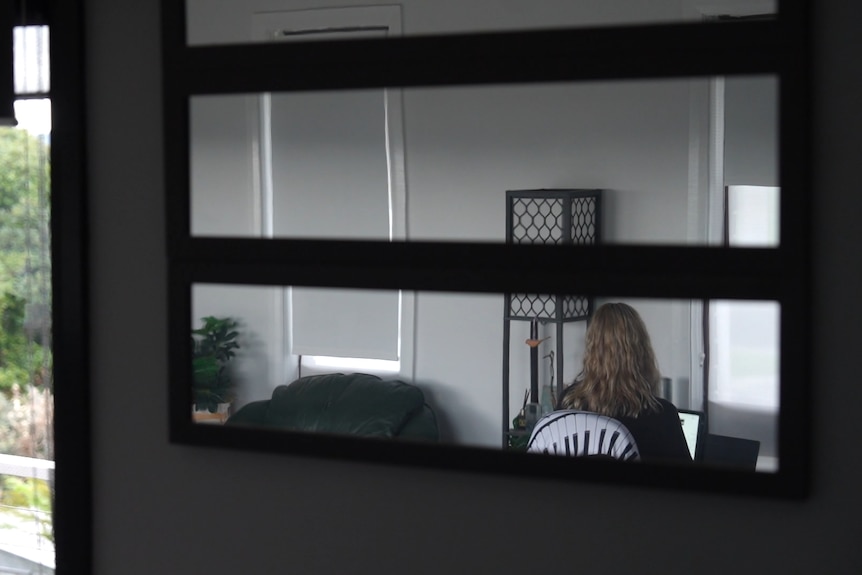 A mirror shows a woman playing the piano