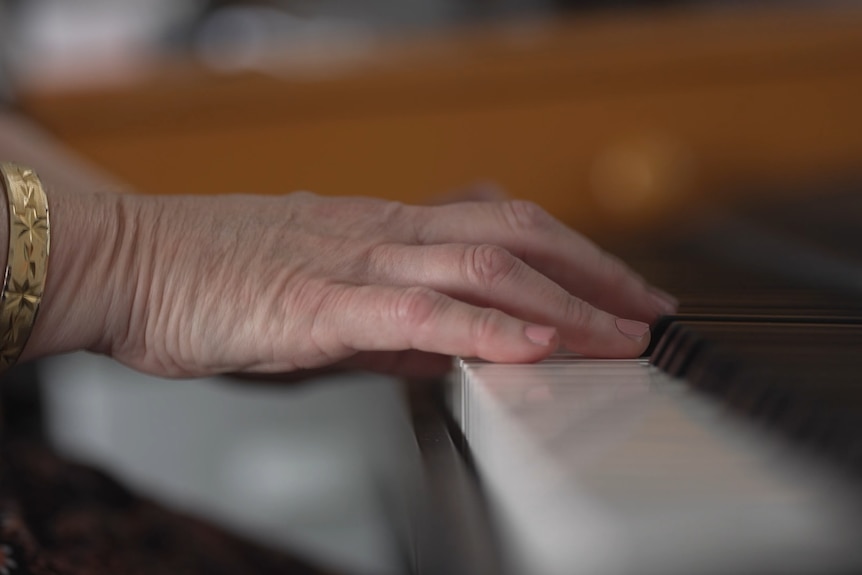 Hands play the keys of a piano