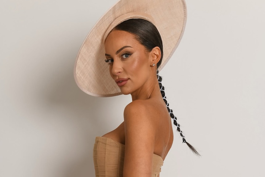 A picture of a woman with a ponytail with a large brown hat