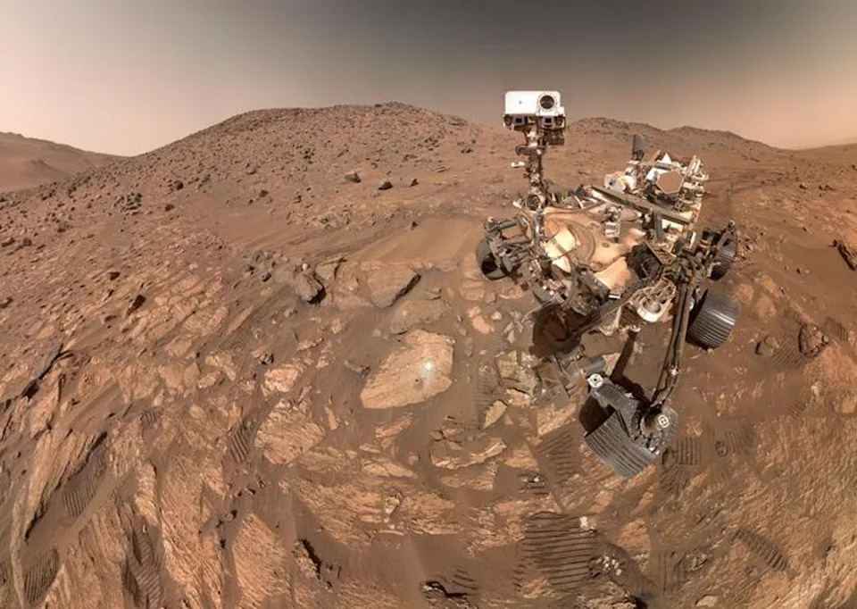 NASA's Perseverance Mars rover is seen in a selfie in July 2024 with the arrowhead-shaped Mars rock nicknamed Cheyava Falls in the Bright Angel region of the planet’s Jezero Crater. The rover collected two mudstones there that have complex carbon (NASA/JPL-Caltech/MSSS)