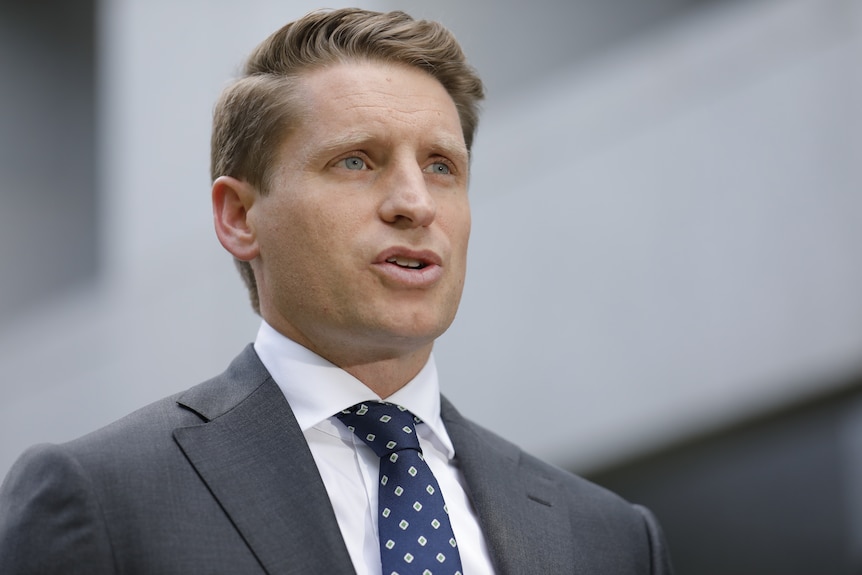 Andrew Hastie speaks, looking across the camera, wearing a suit.