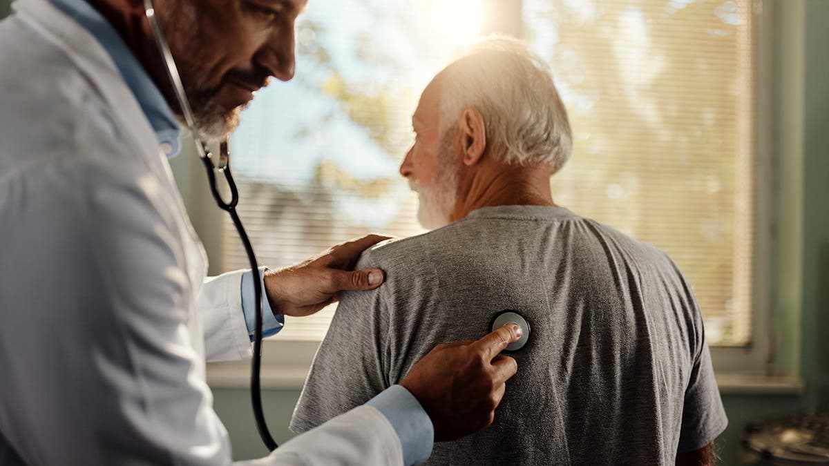 A doctor listens to a man's lungs.