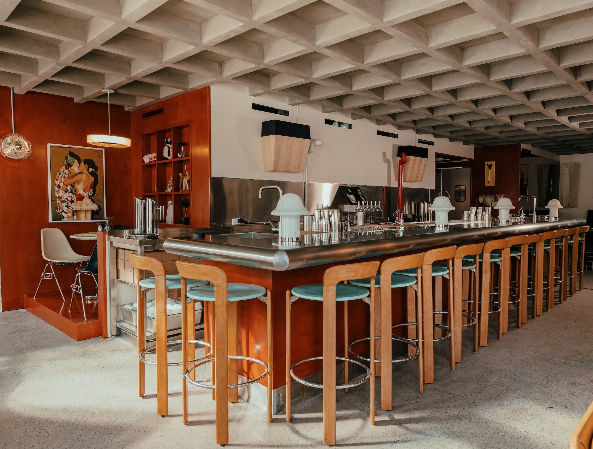 A concrete heavy room with a steel bar and wooden chairs