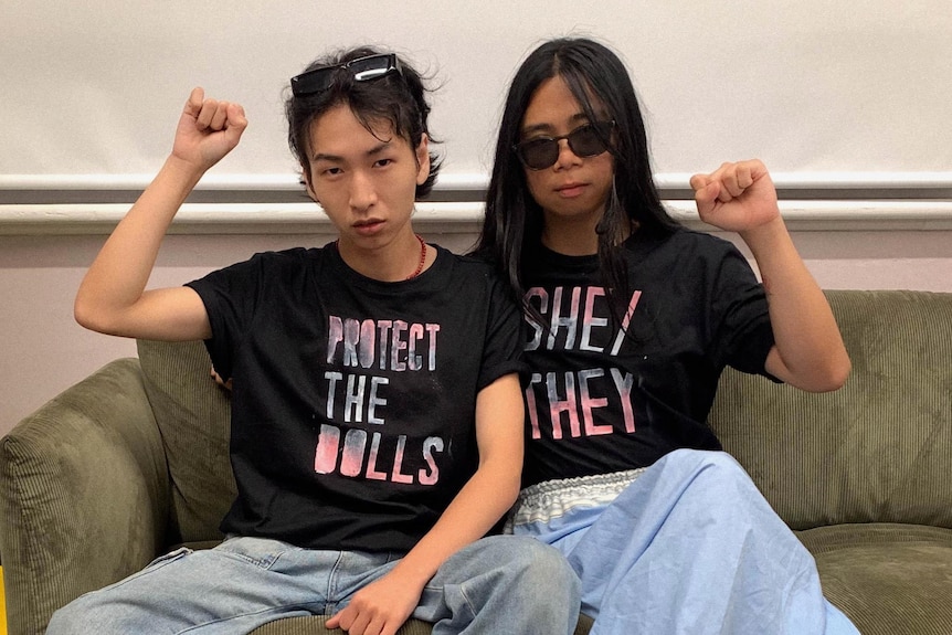 Damien Nguyen and Luna Choo wearing black tops with 'protect the dolls' and 'she/they'