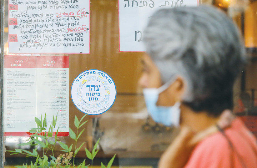 A WOMAN walks past a Jerusalem eatery with a Tzohar kashrut certificate.