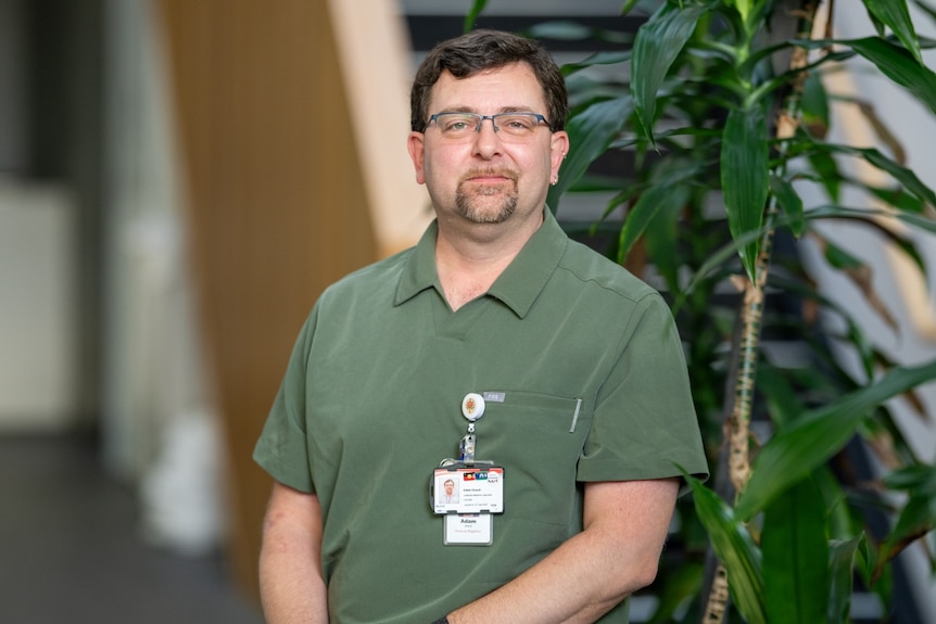 A photo of a man in a polo, with glasses, sitting in indoors.