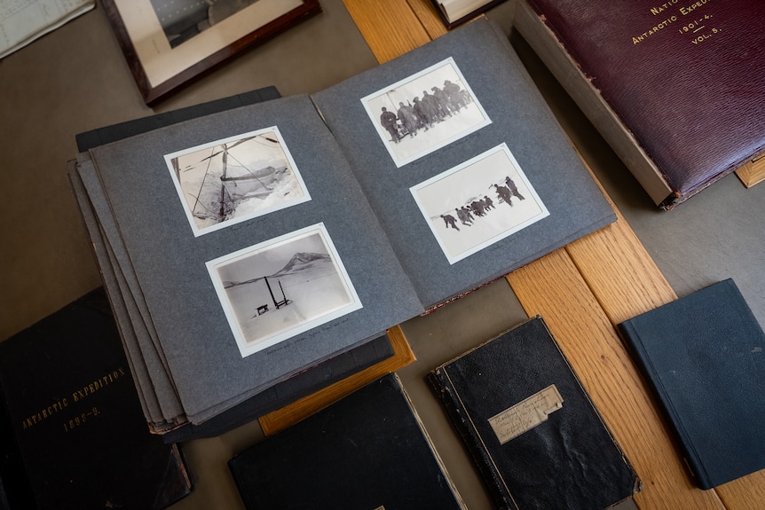 Black and white photos from Shackleton's Antarctic expedition sit in bound books