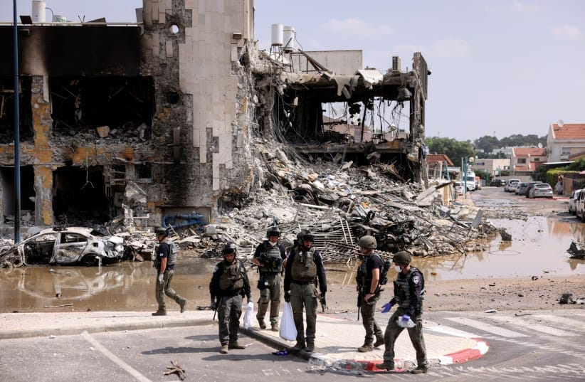  Israeli security gather near a rifle at the site of a battle following a mass infiltration by Hamas gunmen from the Gaza Strip, in Sderot