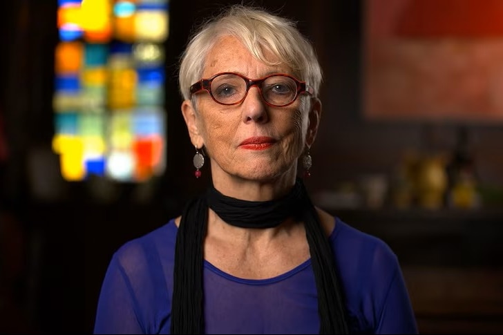 a woman wearing red glasses sitting staring at the camera