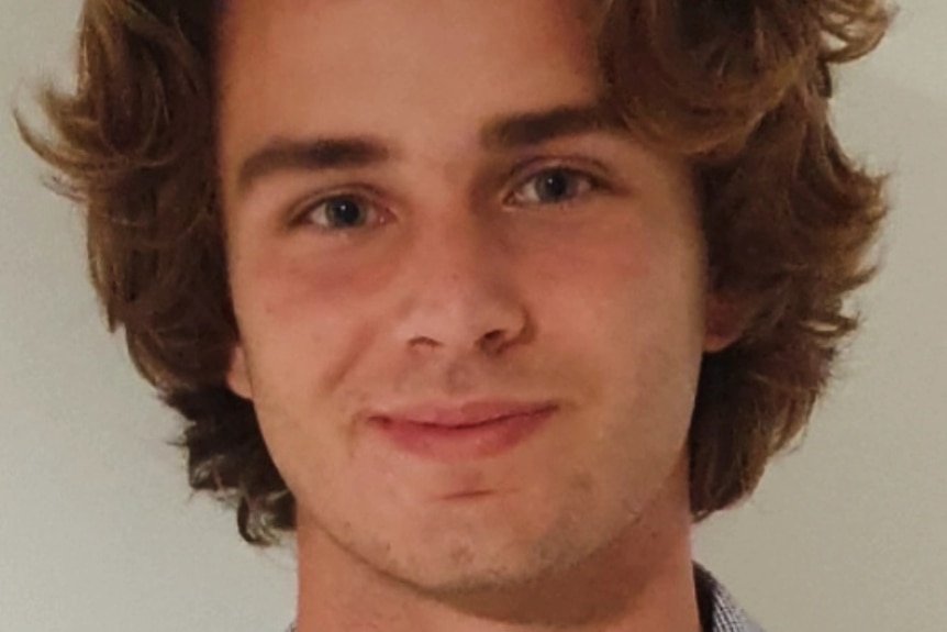 A young man smiles for a portrait.