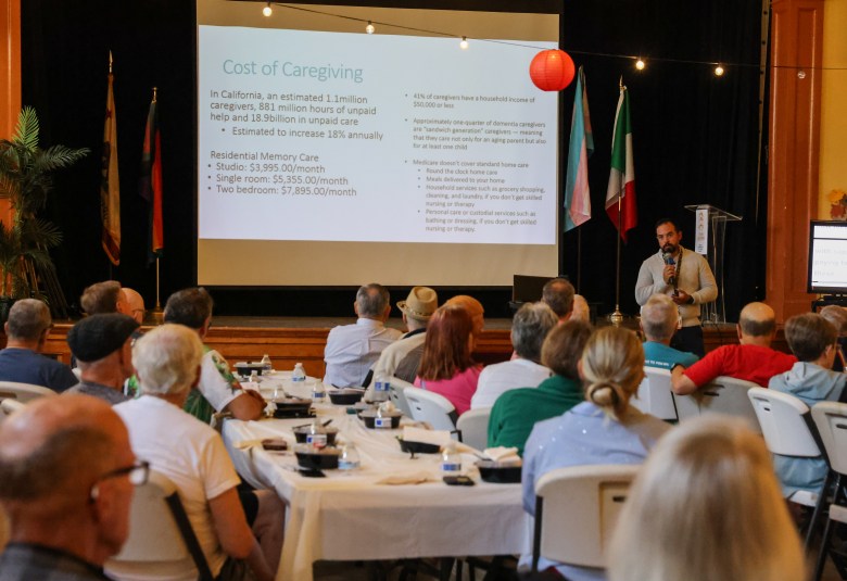Seniors sit while man holds a mic beneath powerpoint