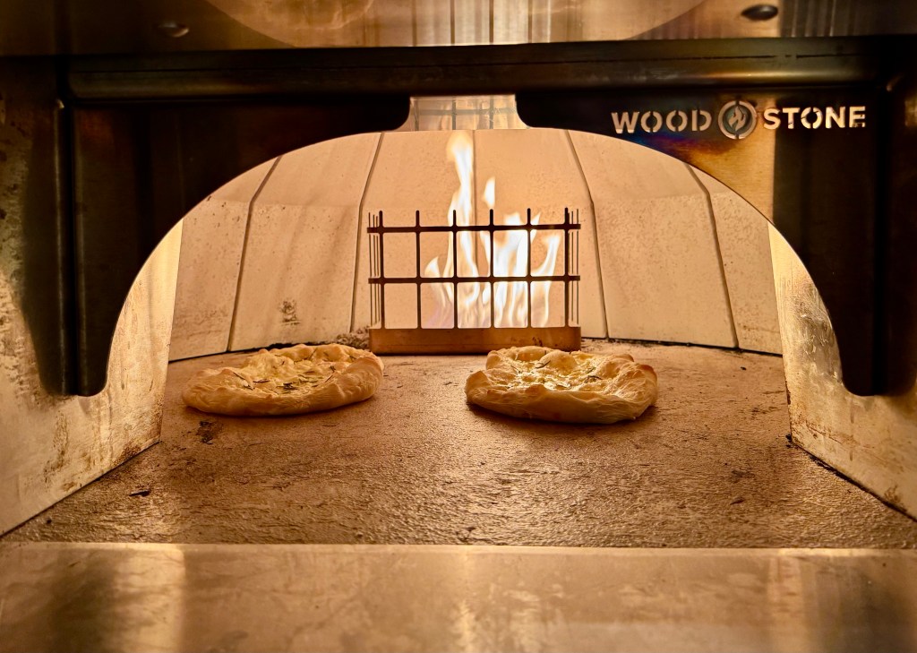 Two pizza Bianca bake in a wood-fired pizza oven.