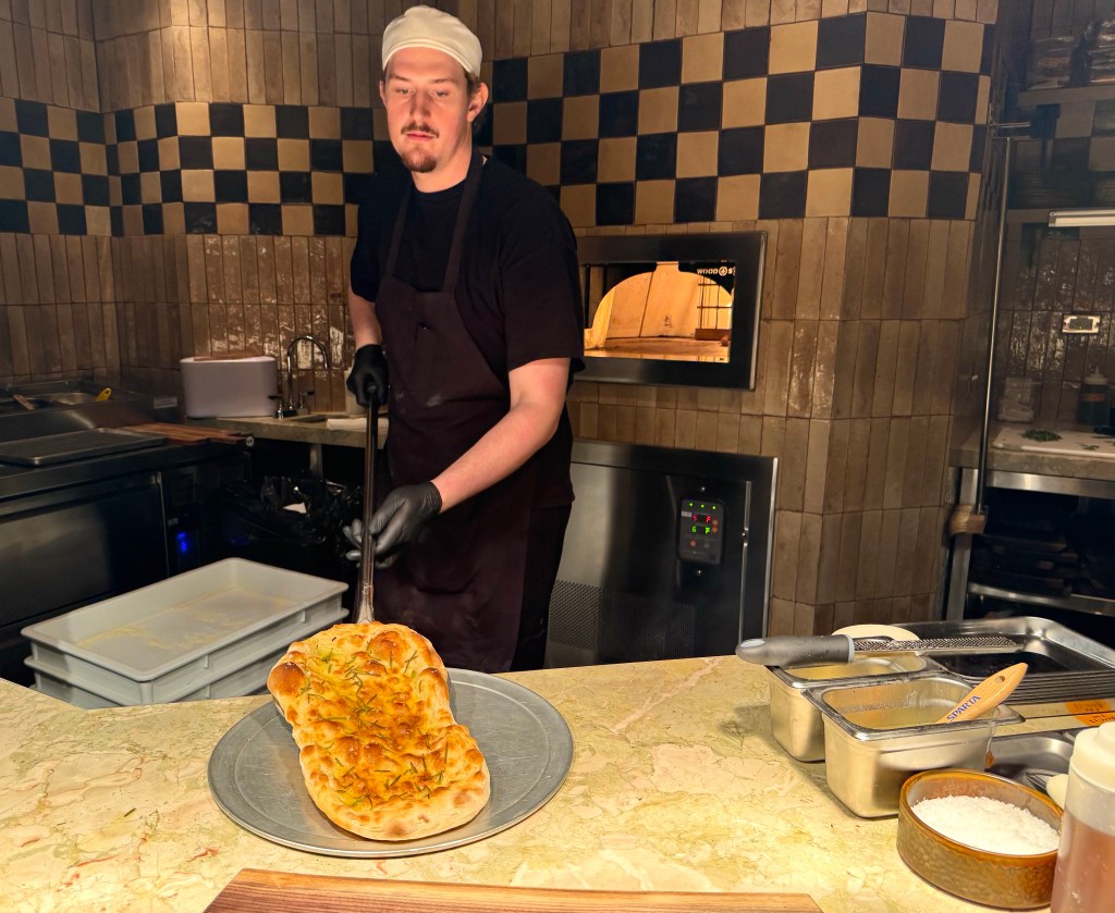 A chef pulls a pizza bianca from the oven.
