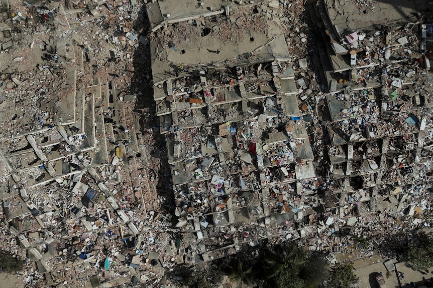 An aerial shot of a large area cluttered by concrete rubble where tower buildings have collapsed.