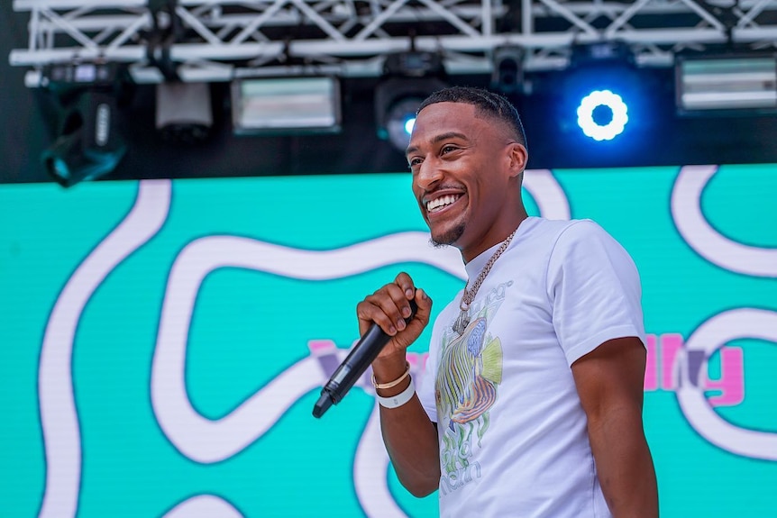 Yung Filly smiling on stage holding a microphone.