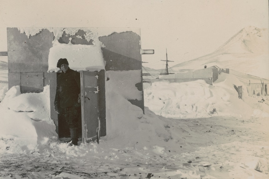 Australian physicist Louis Bernacchi stands in a doorway surrounded by ice on Antarctica