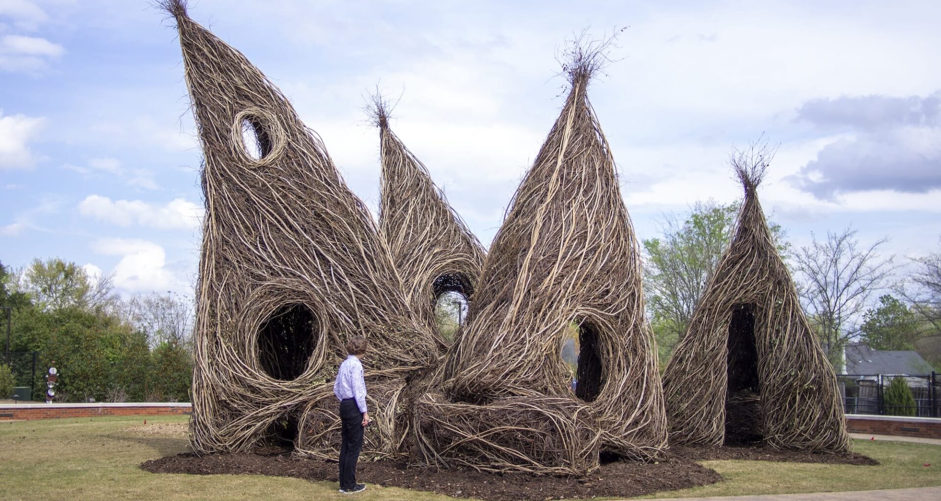 a whimsical, architectural public art sculpture made from interwoven twigs and saplings