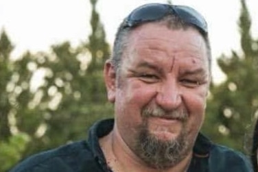 A man in a black shirt smiling