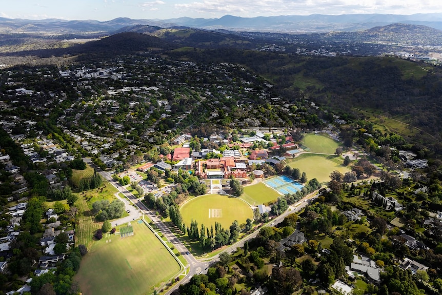 Canberra Grammar School from the air, with orange-tiled roofs among green grass, trees and housing.
