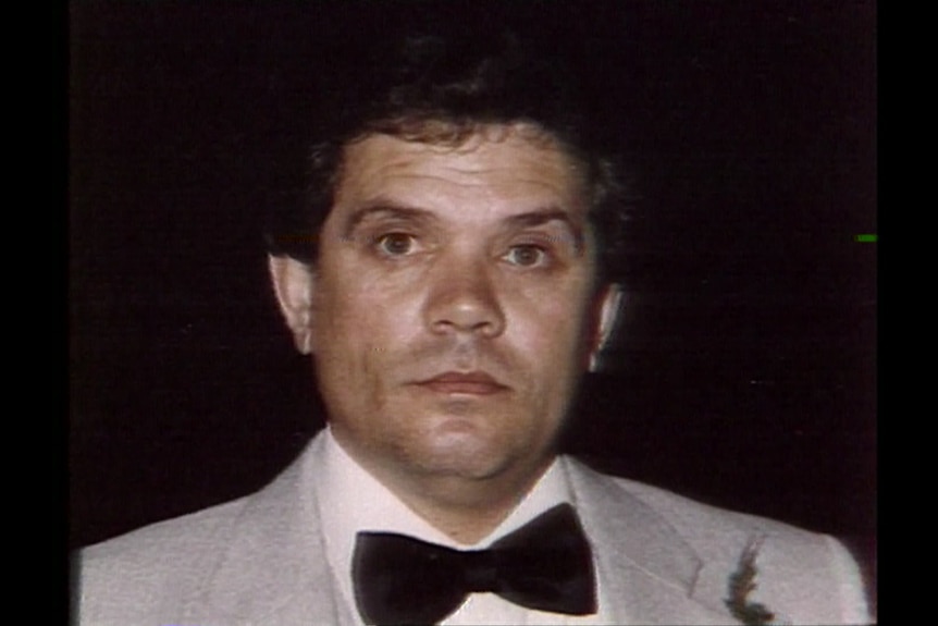 A man in a grey suit and dark bowtie