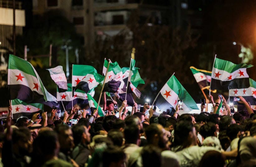 People wave Syrian flags as they gather at Umayyad Square in Damascus to watch a broadcast of Syrian President Ahmed Al-Sharaa delivering a speech at the United Nations, in Syria, September 24, 2025.