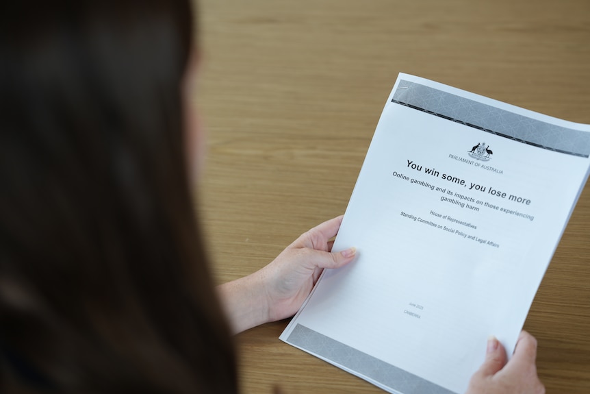 A dark-haired woman holds a report called "You win some, you lose more".