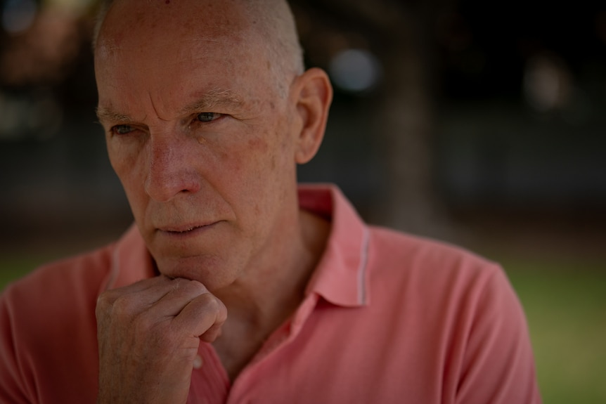 Michael O'Connell wears a salom coloured collared shirt and rests his chin in his hand