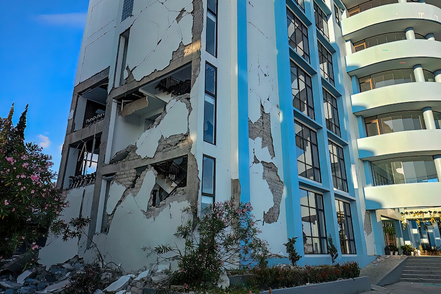 A multi-storey building with parts of walls missing and exposed rooms.