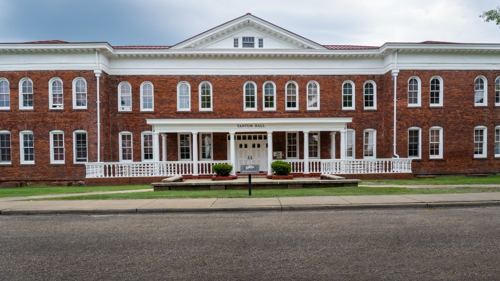 Tantum Hall, a brick building with white trim, arched windows on the second floor, and a white-columned porch, at Tuskegee University.