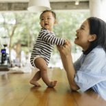 Candid shot happiness and togetherness Asian mother supporting daughter try to standing and walking first time and positive emotion - stock photo
