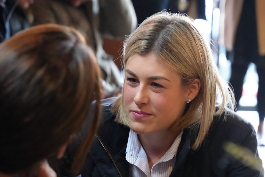 A young woman with blonde hair is crouching listening to a woman with brown hair