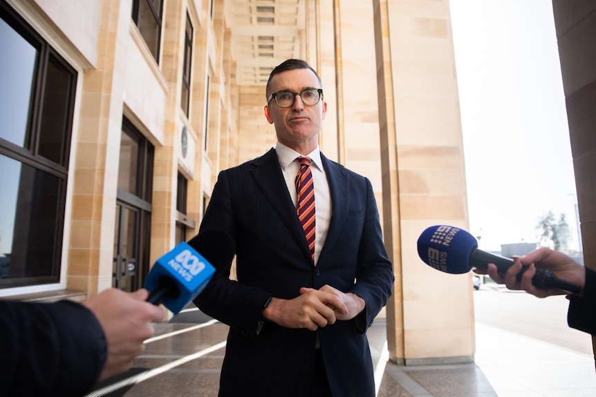 John Carey looks squarely at the camera as he stands in front of WA Parliament